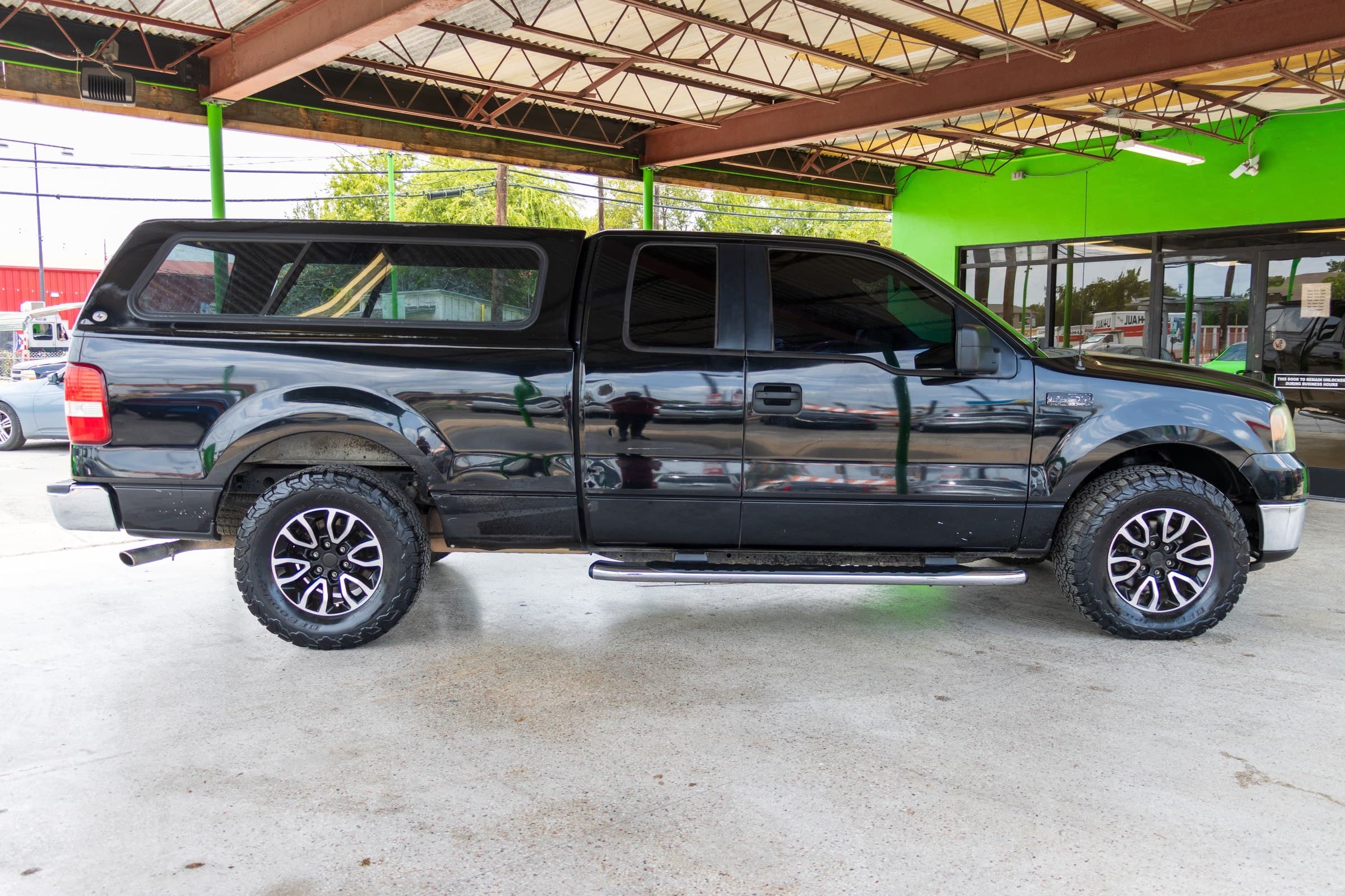 Full passenger-side profile of the F-150, showing the extended cab, the camper shell over the bed and the chrome running board.