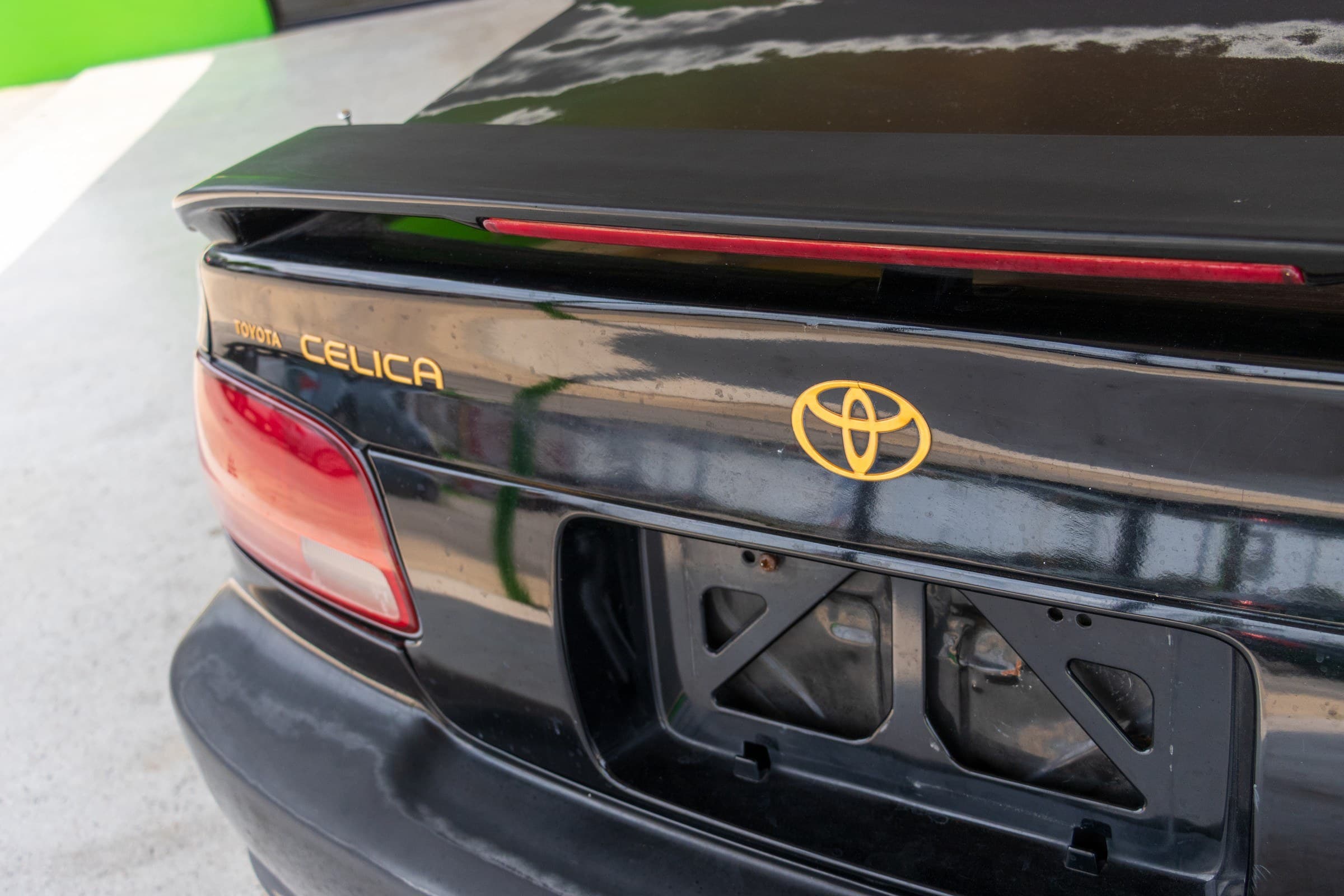 Close-up of the Celica's trunk badging: gold Toyota, Celica and GT lettering above the license plate recess.