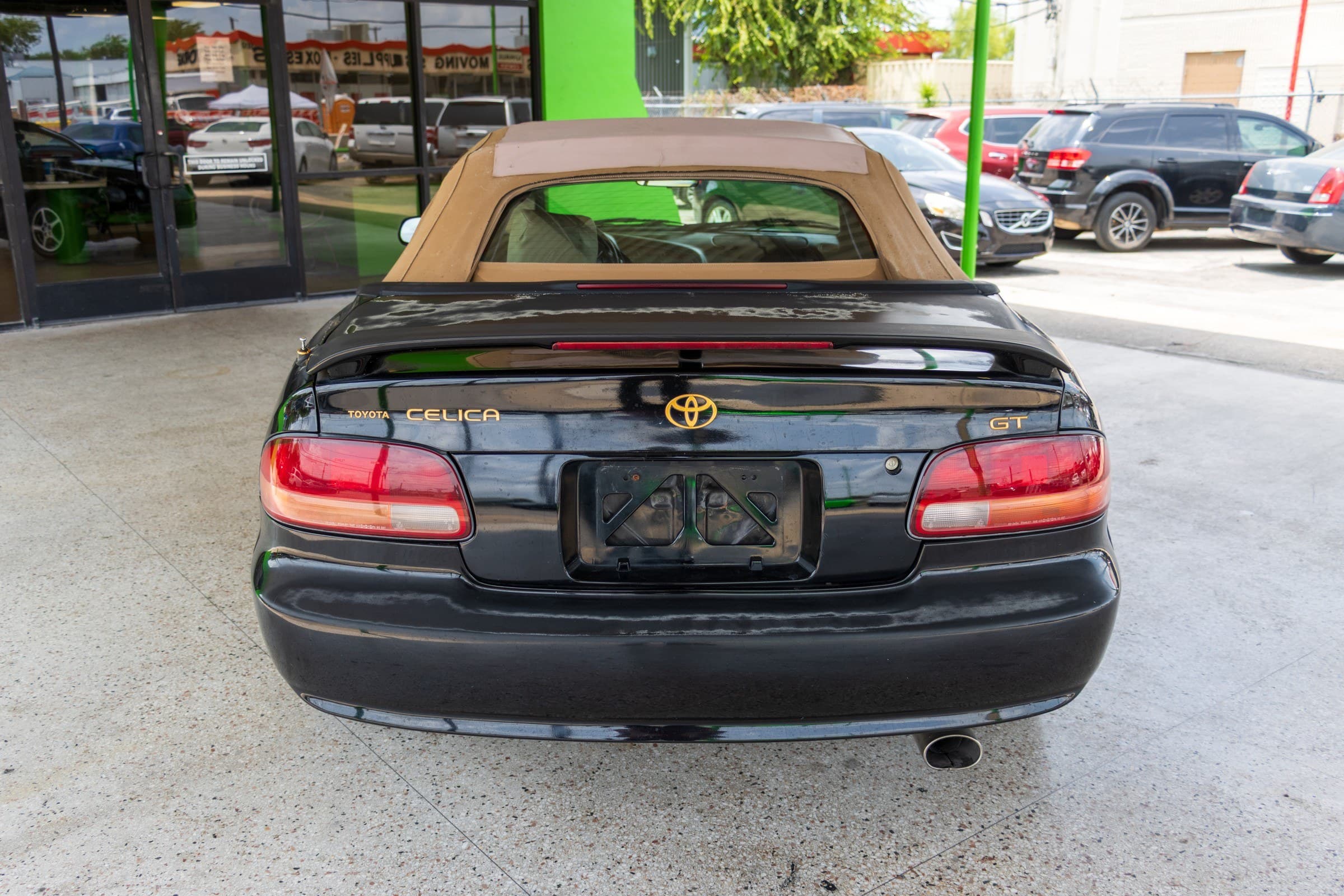Rear view of the Celica convertible, showing the tan soft top, trunk spoiler and gold Toyota, Celica and GT badging.