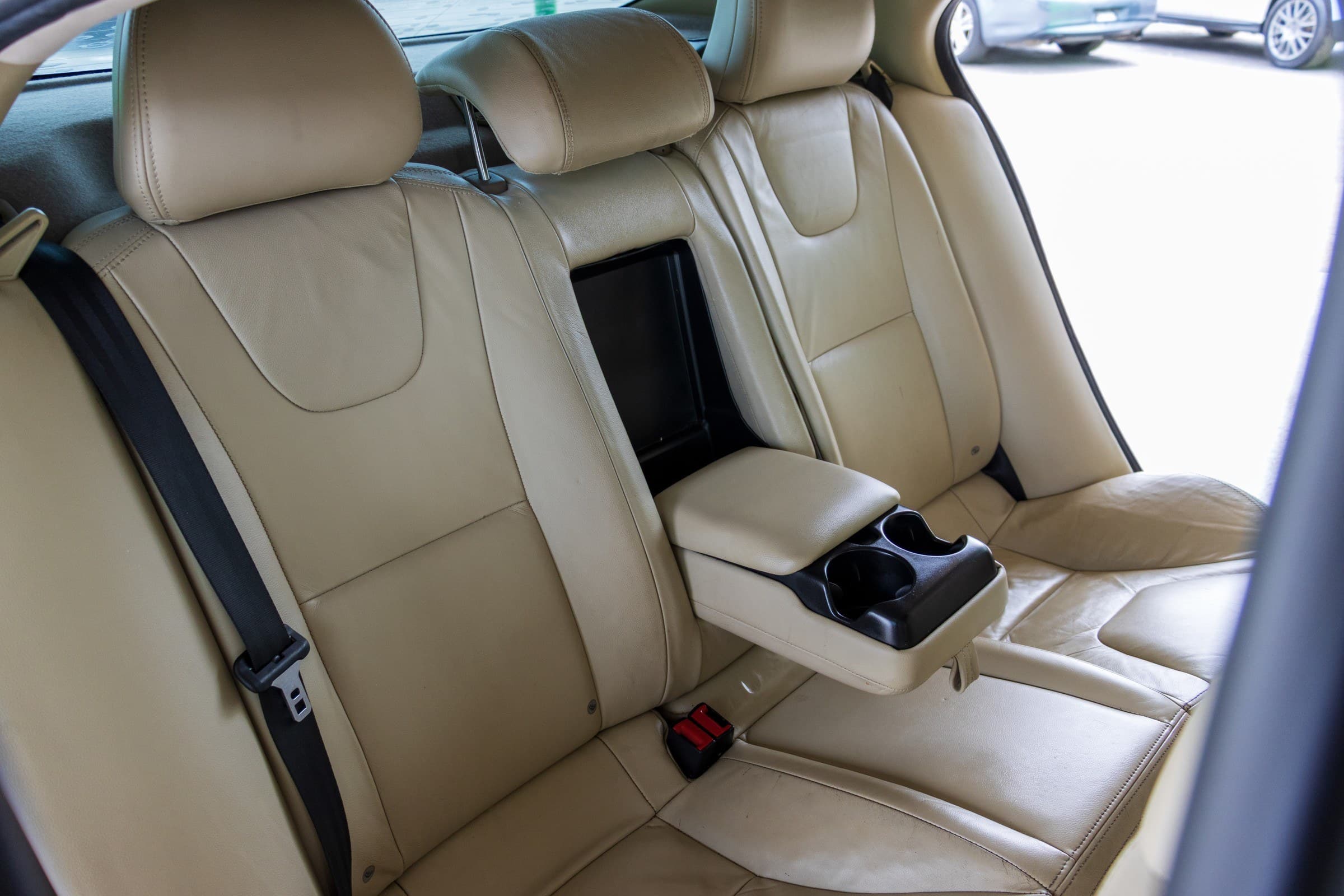 Tan leather rear bench of the S60 with the center armrest and cupholders folded down.