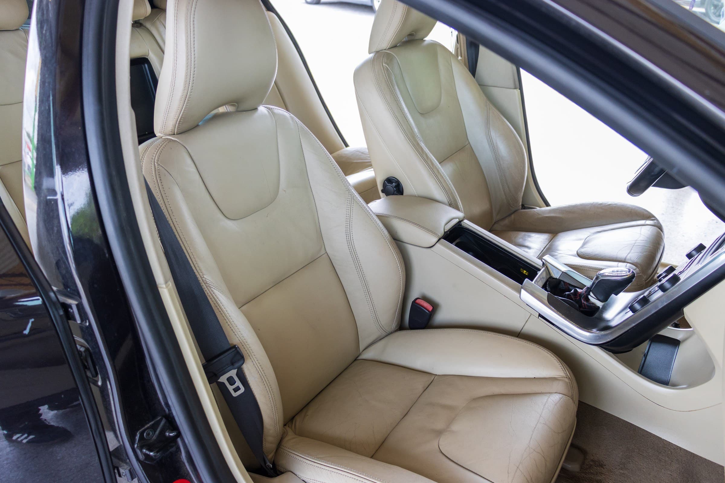 The S60's tan leather front seats seen through the open driver's door.