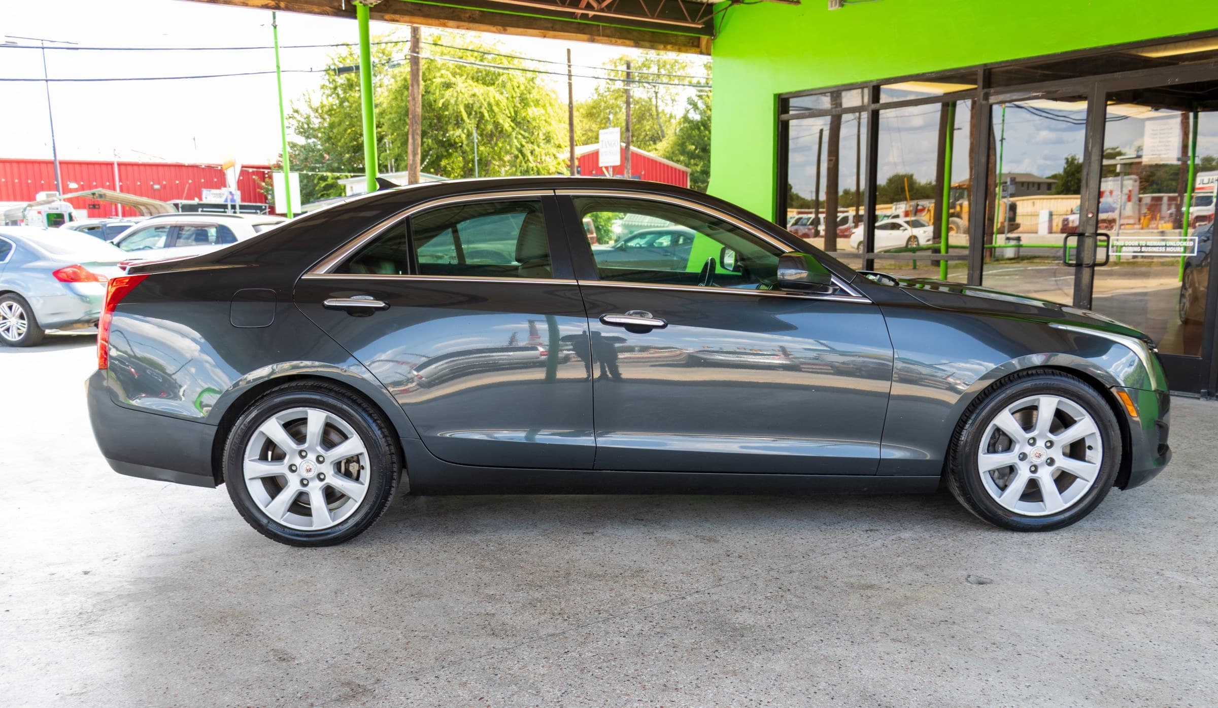 Full passenger-side profile of the dark gray Cadillac ATS, showing its silver multi-spoke alloy wheels.