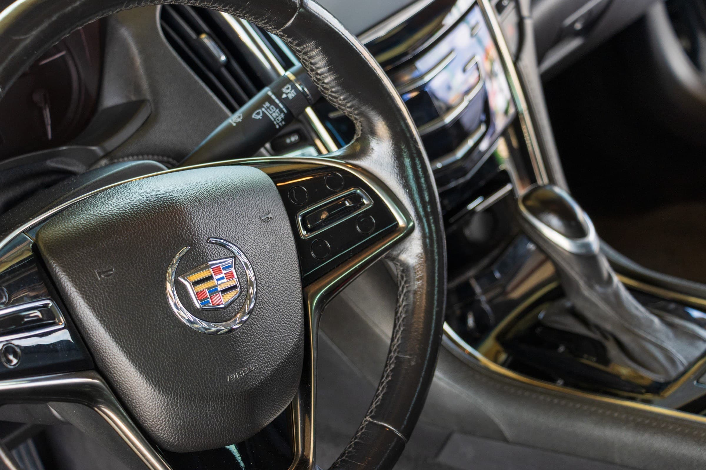 Close-up of the ATS steering wheel and its Cadillac crest, with the centre console shifter behind it.