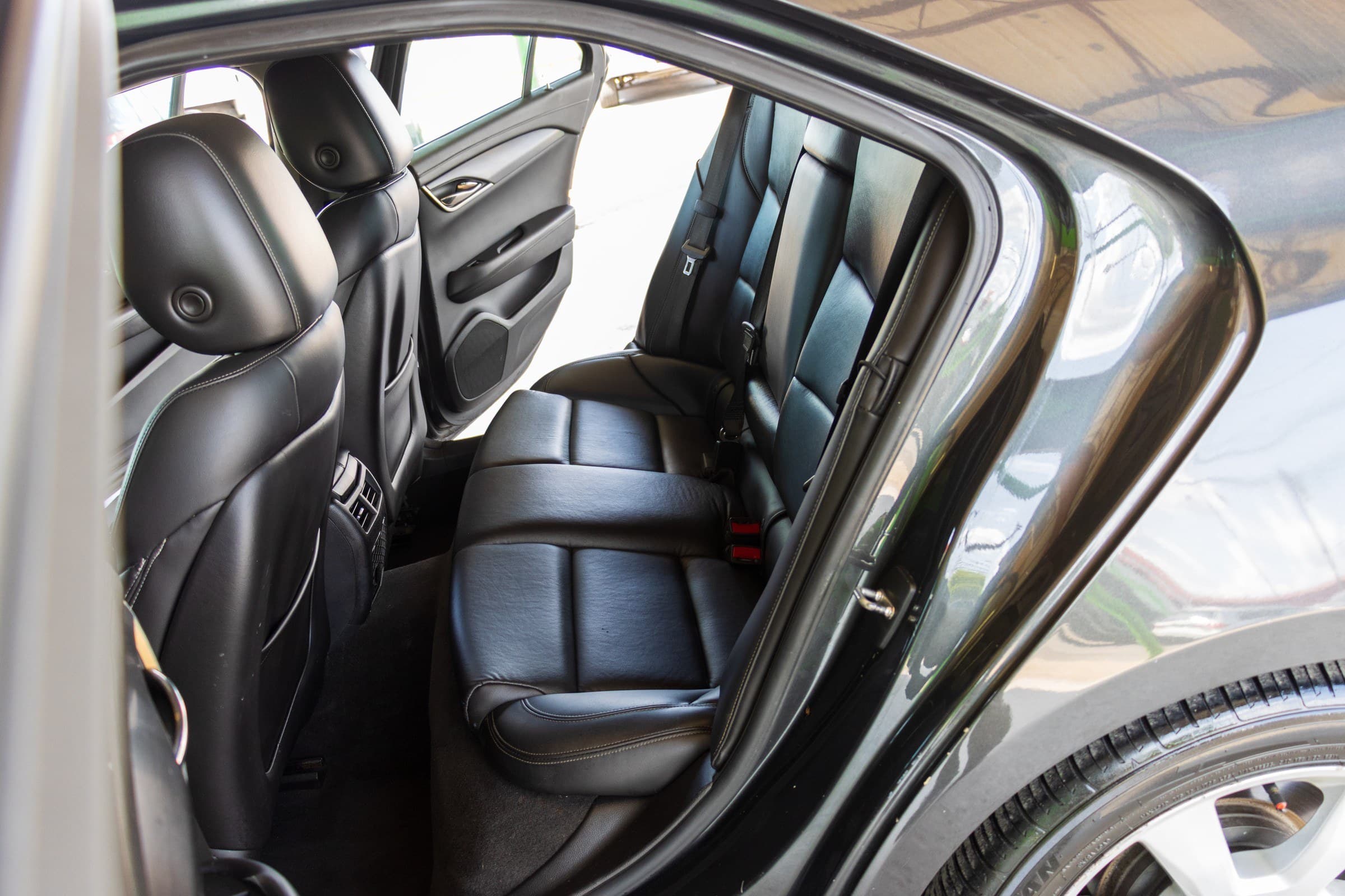 Black leather rear seats of the Cadillac ATS seen through the open driver-side rear door.