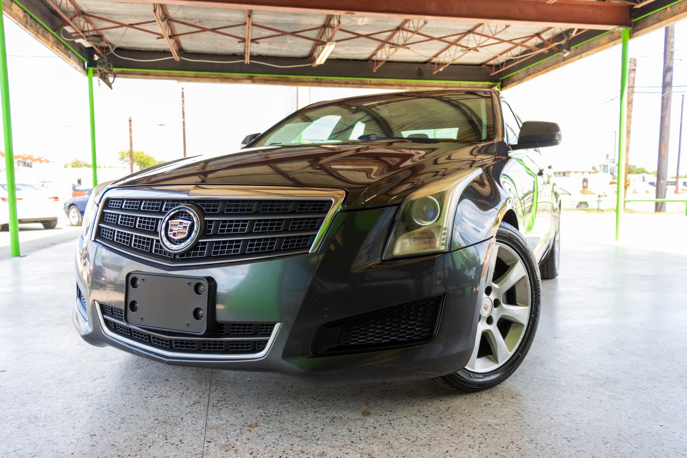 Dark gray metallic 2014 Cadillac ATS sedan seen from a low front angle, showing the chrome grille and Cadillac crest badge.