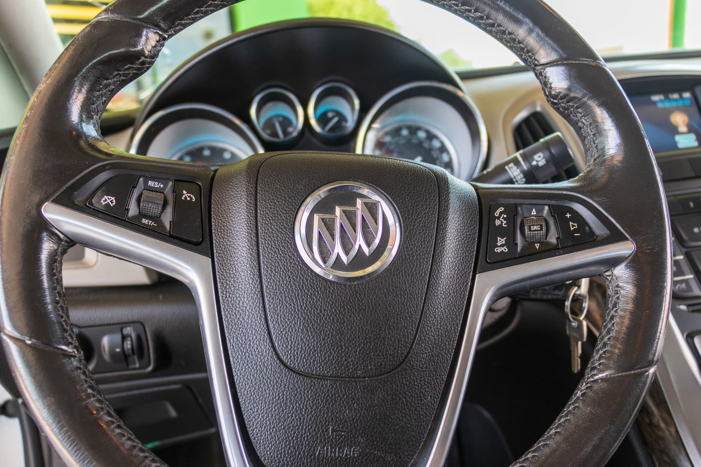Close-up of the Verano's steering wheel, showing the Buick badge and the cruise control and audio buttons on the spokes.
