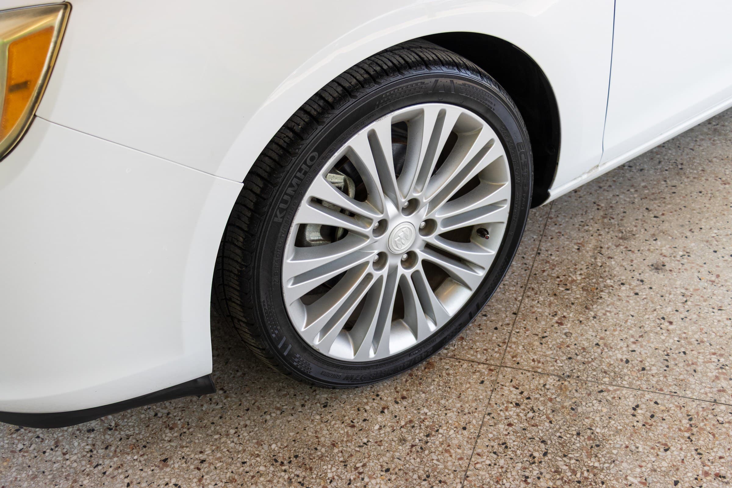 Close-up of a silver Buick alloy wheel and tire on the white Verano.
